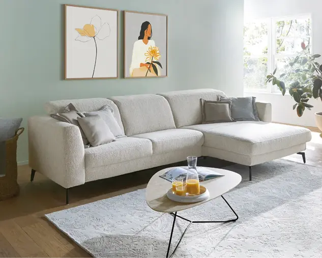 Helles Wohnzimmer mit modernem Ecksofa, Dekokissen und Couchtisch. Zeitlose Wohnmöbel schaffen eine gemütliche Atmosphäre und zeigen zeitgemäßes Wohndesign für stilvolles Einrichten.